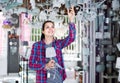 Girl in lighter shop choosing modern glass chandelier for house Royalty Free Stock Photo