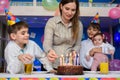 Girl lights candles on a pie at the festive table Royalty Free Stock Photo