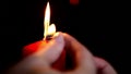 The girl lights a large red candle on the background of boke. Close-up of a burning candle.