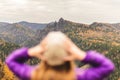 A girl in a lilac jacket looks out into the distance on a mountain, a view of the mountains and an autumnal forest by an overcast Royalty Free Stock Photo