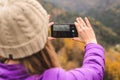 A girl in a lilac jacket takes pictures on a telephone in the mountains, an autumn forest with a cloudy day