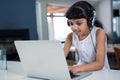 Girl listening music from headphones while using laptop Royalty Free Stock Photo