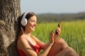 Girl listening to the music and downloading songs in a field