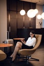 Girl listening to music through headphones on the tablet at business lounge at the airport.