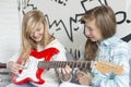 Girl listening to sister playing electric guitar at home