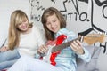 Girl listening to sister playing guitar at home