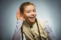 Girl listens. child hearing something, hand to ear gesture on grey background.