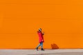 A girl listens to music with headphones on the background of an orange wall . Copy space. Mockup. An article about Royalty Free Stock Photo