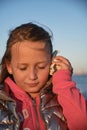 a girl listens to a seashell on the beach Royalty Free Stock Photo