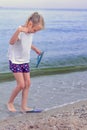 Girl, a little blonde, 6 years old, standing on the sand by the sea, the child is having fun playing by the sea on the beach Royalty Free Stock Photo