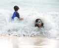 Girl and little brother hit by big wave Royalty Free Stock Photo