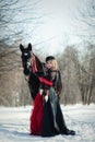 A girl in a long black dress with a dark horse Royalty Free Stock Photo