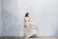 Girl with long black hair in a gentle silk wedding dress in pastel color