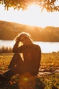 Girl with long blond hair in autumn landscape at sunset. Portrait of a girl sitting on the grass, selective focus Royalty Free Stock Photo