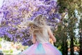 A girl with a long blond hair near the jacaranda tree in a full bloom with beautiful purple flowers Royalty Free Stock Photo