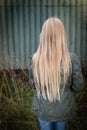 Girl with long blonde hair from behind by a rusty green wall Royalty Free Stock Photo