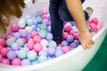 Girl with long blonde hair in blue jeans breaks into the pool with plastic balls of pastel colors pink, white, purple Royalty Free Stock Photo