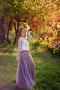 A girl with long braids in a white blouse stands in the rays of the setting sun