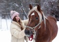 Girl with long brown hair and chestnut horse with plaited mane close up portrait on winter snowy background