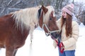 Girl with long brown hair and chestnut horse with plaited mane close up portrait on winter snowy background