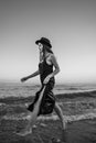 girl in long dress and hat enters thoughtfully into raging sea