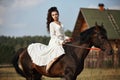 Girl in a long dress riding a horse, a beautiful woman riding a horse in a field in autumn. Country life and fashion, noble steed Royalty Free Stock Photo