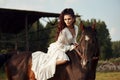 Girl in a long dress riding a horse, a beautiful woman riding a horse in a field in autumn. Country life and fashion, noble steed Royalty Free Stock Photo