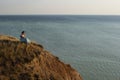 A girl in a long dress sits on a cliff by the sea Royalty Free Stock Photo