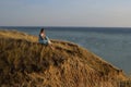 A girl in a long dress sits on a cliff by the sea Royalty Free Stock Photo