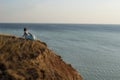 A girl in a long dress sits on a cliff by the sea Royalty Free Stock Photo