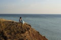 A girl in a long dress sits on a cliff by the sea Royalty Free Stock Photo