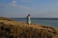 A girl in a long dress standing on a cliff by the sea