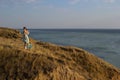 A girl in a long dress standing on a cliff by the sea