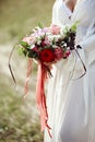 Girl in a long dress stands in a field with wreath on her head and bouquet of flowers in her hands, beautiful woman in the rays of Royalty Free Stock Photo