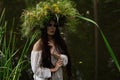 Girl in long dress and wreath is dipping into river