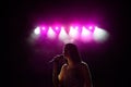 Girl in long gown performing on stage. Girl singing on the stage in front of the lights. Silhouette of singer standing Royalty Free Stock Photo