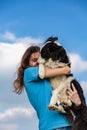 A girl with long hair in a blue T-shirt holds a black and white border collie dog in her hands and hugs. Portrait Royalty Free Stock Photo