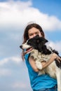 A girl with long hair in a blue T-shirt holds a black and white border collie dog in her hands and hugs. Portrait Royalty Free Stock Photo