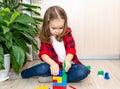 A girl with long hair builds from a plastic construction kit. The girl plays at home Royalty Free Stock Photo