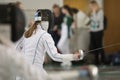 A girl with long hair having fencing duel on tournament. A girl holding a saber