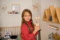 Girl with long hair in pink sweater in children`s room of  youngest child in family, climbed to wall shelves with toys and Royalty Free Stock Photo