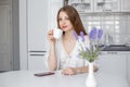 A girl with long hair sits at a table in her modern kitchen, drinking tea or coffee Royalty Free Stock Photo