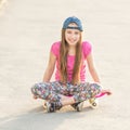 Girl with long hair sitting on skating board Royalty Free Stock Photo