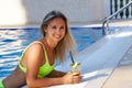 Happy tanned girl drinks cool delicious mahito with ice by the pool on vacation Royalty Free Stock Photo