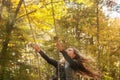 A girl with long hair swinging on a swing in an autumn park. Royalty Free Stock Photo