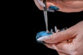 A girl with a long manicure applies blue powder to a brush. Small particles of powder are all around. close-up