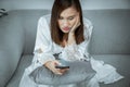 A girl in long sleepwear holding the smartphone in living room