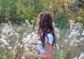 Girl with long wavy hair in a clearing with fluffy seeds of plants. Plants with fluffy seeds Royalty Free Stock Photo