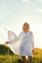 Girl in a long white dress dancing in the field. Blonde woman in the sun in a light dress. Girl resting and dreaming, perfect Royalty Free Stock Photo