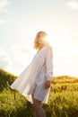 Girl in a long white dress dancing in the field. Blonde woman in the sun in a light dress. Girl resting and dreaming, perfect Royalty Free Stock Photo